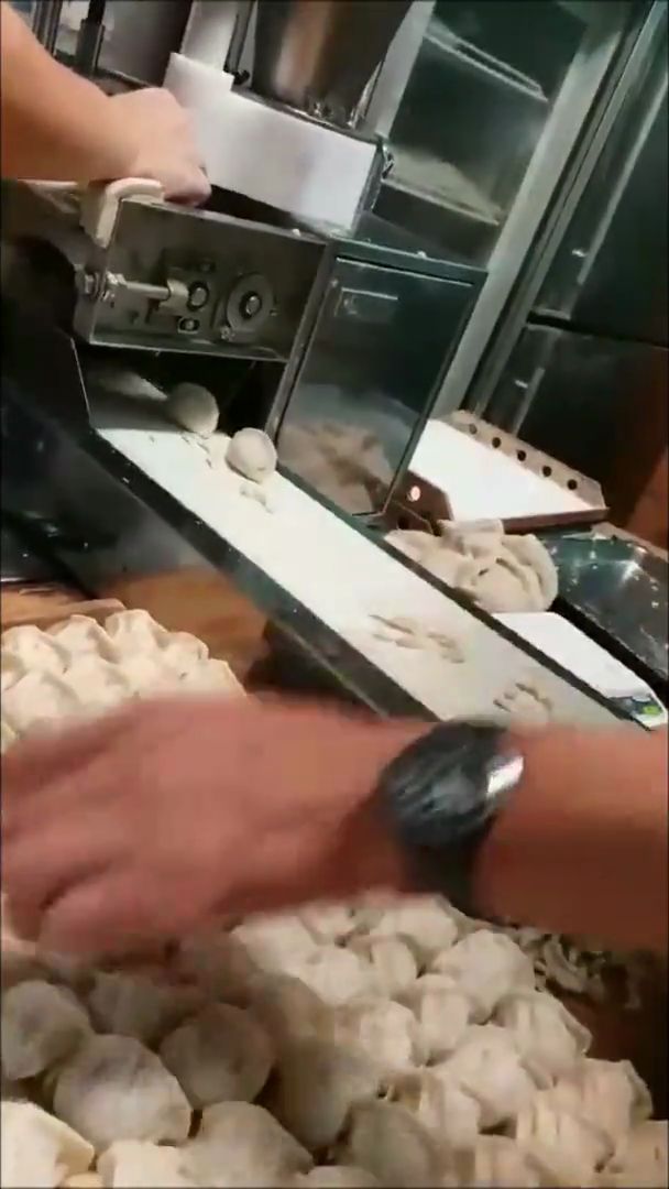 操作人員整理輸送帶上做好的水餃